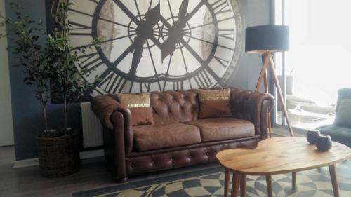 un divano marrone in un soggiorno con un grande orologio di Apartamento Boutique Viña del Mar a Viña del Mar
