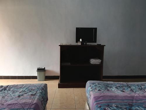 Habitación con cama y TV en un estante. en Km 31 Sujono Guesthouse, en Bromo