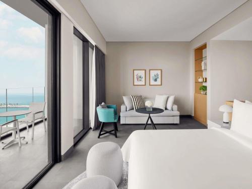 a bedroom with a bed and a couch and a table at Mövenpick Resort Al Marjan Island in Ras al Khaimah