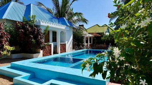 a swimming pool in front of a house at Vyogo Blue Villa Jambiani in Mfumbwi