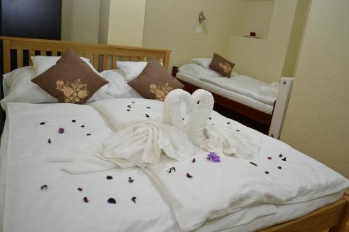 two white swans sitting on top of a bed with flowers at Ezüstfenyő Hotel in Telkibánya