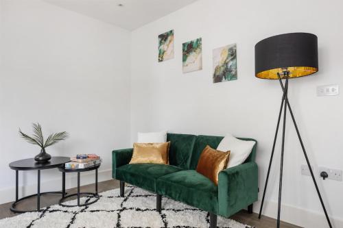 a green couch in a living room with a floor lamp at Stonebridge House Apartment in Chelmsford