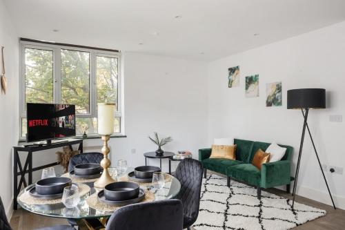 a living room with a table and a green couch at Stonebridge House Apartment in Chelmsford