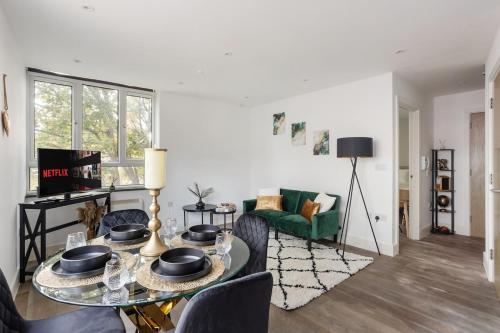 a living room with a table and a green couch at Stonebridge House Apartment in Chelmsford