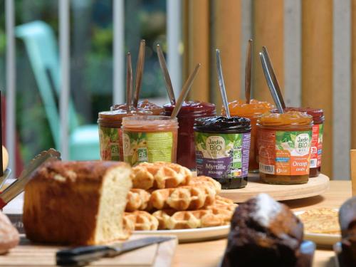 una mesa cubierta con tarros de comida y pan en ibis Budget La Rochelle Centre gare, en La Rochelle