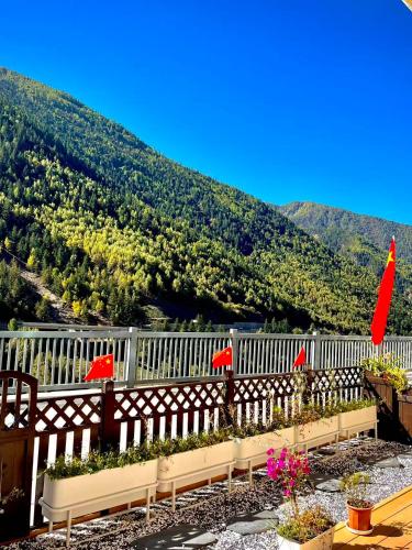 a white fence with some plants and red umbrellas at Buyandujiajinpinminsu in Mount Siguniang