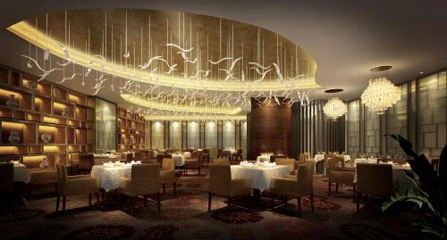 a restaurant with white tables and chairs and a chandelier at Grand Skylight International Hotel Ganzhou Chang Zhen Avenue in Ganzhou
