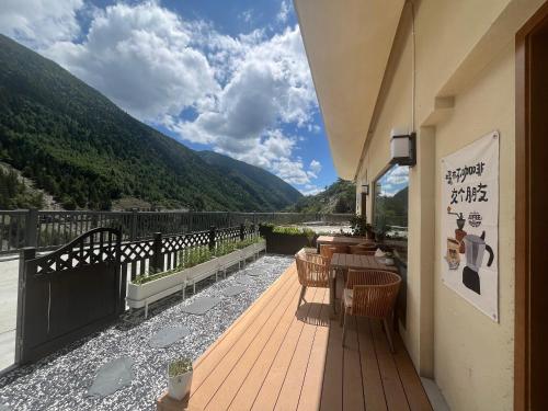 a wooden deck with tables and chairs on a balcony at Buyandujiajinpinminsu in Mount Siguniang