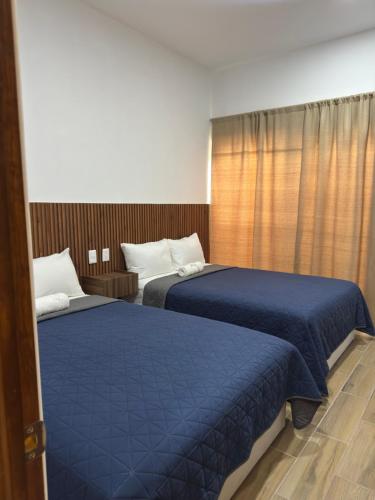 two beds in a hotel room with blue sheets at Hotel Mochomos Huajuapan in Huajuapan de León
