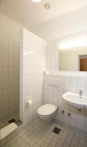 a white bathroom with a toilet and a sink at Sportpark Hugstetten in Hugstetten