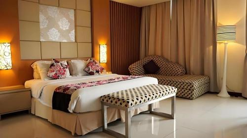 a bedroom with a large bed and a chair at Kedaton Hotel in Bandung
