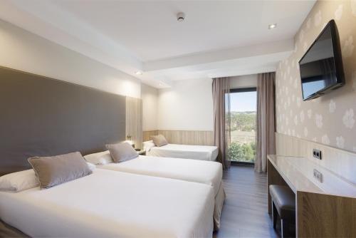 a hotel room with two beds and a flat screen tv at Hotel Civera in Teruel