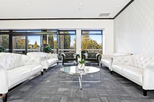 a living room with white couches and a table at Hotel Elms Christchurch, an Ascend Collection Hotel in Christchurch