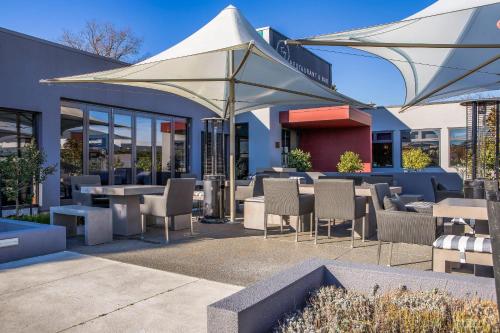 a restaurant with tables and chairs and an umbrella at Hotel Elms Christchurch, an Ascend Collection Hotel in Christchurch