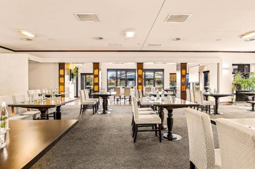 Un comedor con mesas y sillas y ventanas. en Hotel Elms Christchurch, an Ascend Collection Hotel, en Christchurch