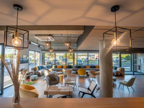 a lobby with couches and tables and chairs at Greet Hôtel Orthez Bearn in Orthez