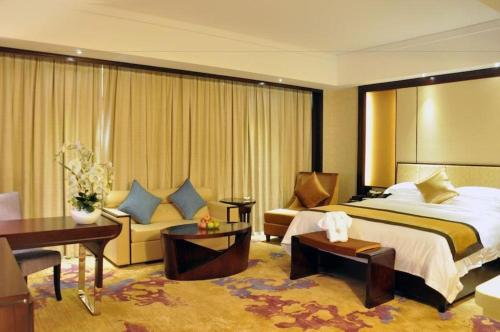 a hotel room with a large bed and a desk at Haikou Conifer Garden Hotel in Haikou