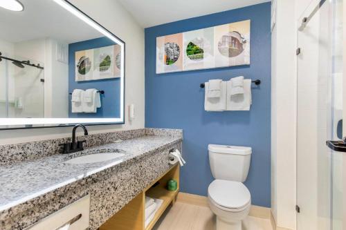 a bathroom with a toilet and a sink with a mirror at Sleep Inn in Manassas