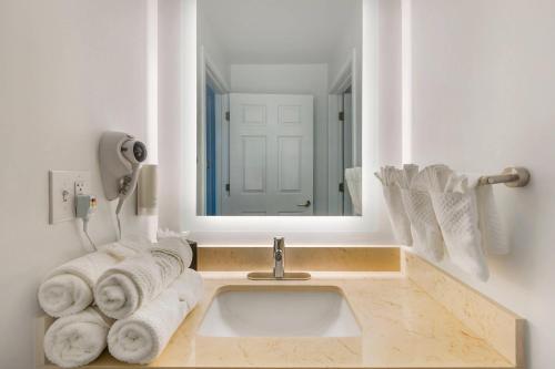 a bathroom with a sink and a mirror and towels at MainStay Suites Sterling near Dulles Town Center in Sterling