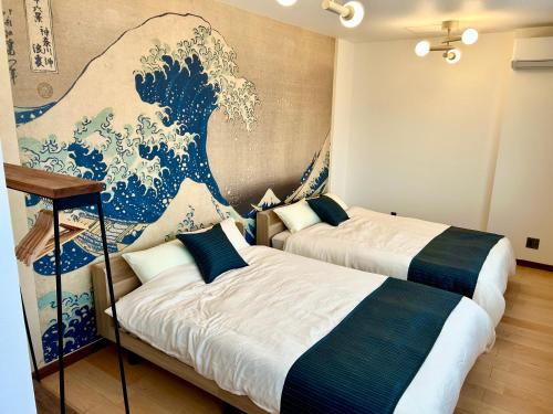 two beds in a room with a painting of a wave at Fuji AK Vacation Rental in Fujiyoshida