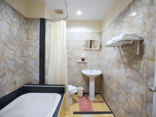 a bathroom with a tub and a toilet and a sink at Night Bazaar Place in Chiang Mai
