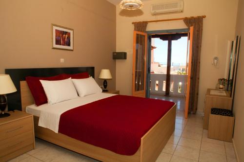 a bedroom with a large bed with a red blanket at Palmira Apartments in Makry Gialos