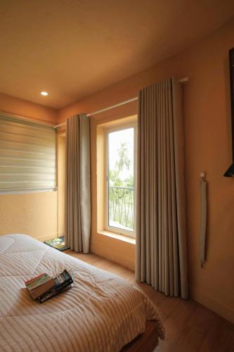 a bedroom with a bed and a window with curtains at Amya home Hoi An in Hoi An