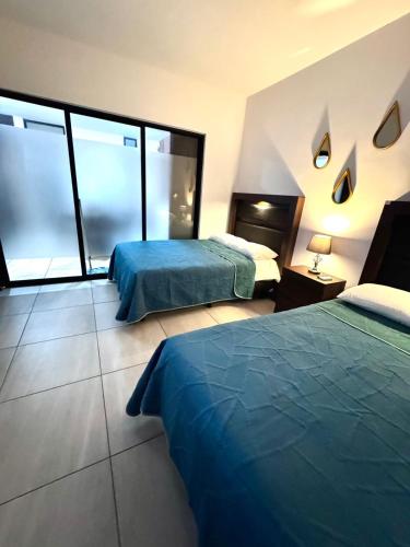 a hotel room with two beds and large windows at Loft, Departamento cerca del Malecon, MAZATLAN in Mazatlán