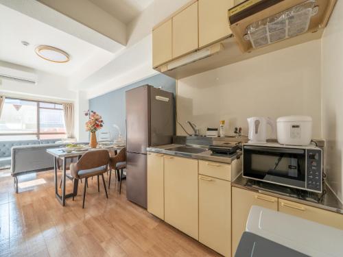a kitchen with a table and a stainless steel refrigerator at Newly opened Hotel 7 京セラドーム徒歩10分 道頓堀 関西空港 大阪城 海遊館直行 USJ1回乗換 出張 Family friendly Free parking 15 minutes by car to USJ in Osaka