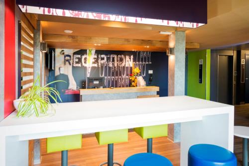 a bar with colorful stools in front of a restaurant at ibis budget Granville in Granville