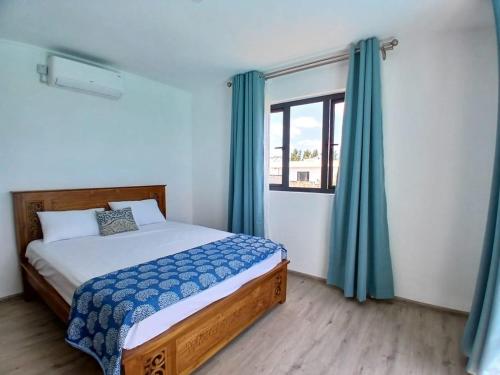 1 dormitorio con 1 cama con cortinas azules y ventana en Villa Esperenza-3 bedrooms, en Flic en Flac