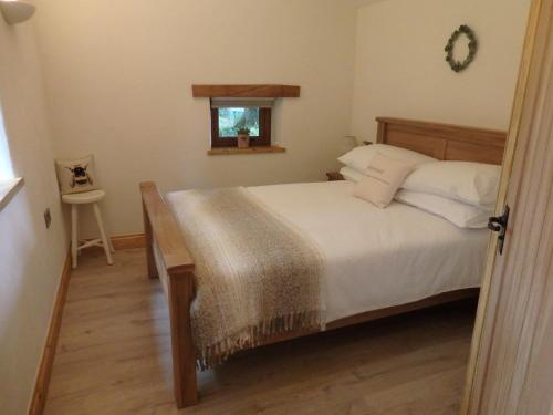 a bedroom with a bed with white sheets and a window at The Potting Shed in Little Torrington
