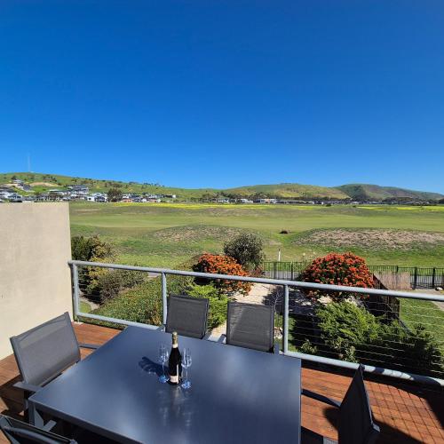 a table on a balcony with a view of a golf course at 19th Hole Golf, Wine & Sea in Normanville