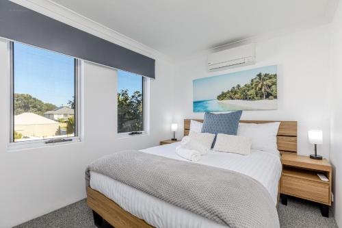 a white bedroom with a large bed and windows at The Palms in Perth