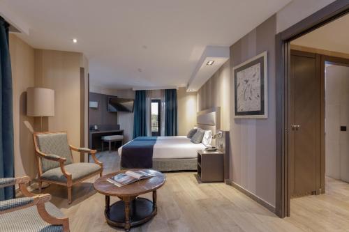 Una habitación de hotel con una cama, una silla y una mesa. en Hotel Reina Cristina, en Teruel