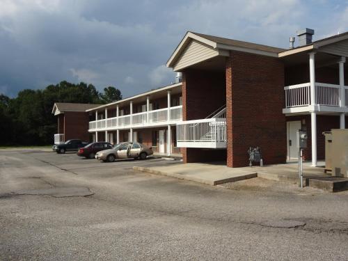 a building with cars parked in a parking lot at Best Inn Formerly Known as M Star Hotel in Chickasaw