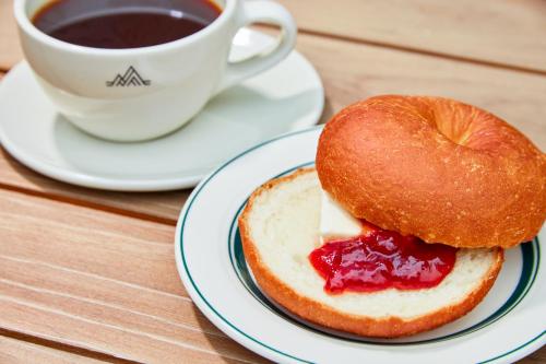 a doughnut and jam on a plate next to a cup of coffee at FAV LUX Nagasaki in Nagasaki