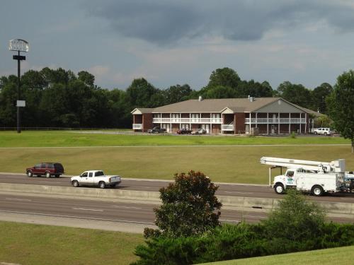 a building with trucks and cars on a highway at Best Inn Formerly Known as M Star Hotel in Chickasaw