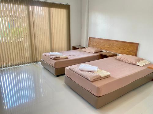 a bedroom with two beds and a large window at โรงแรมบ้านสวน ฟ้าใส in Chanthaburi