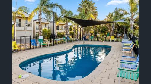 a swimming pool with chairs and a hammock over it at 19th Hole Golf, Wine & Sea in Normanville