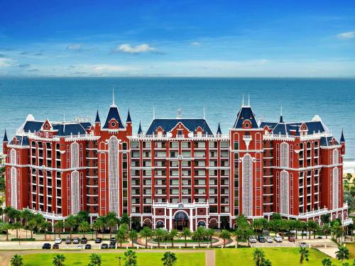 a large resort building with the ocean in the background at Mövenpick Resort Phan Thiet in Phan Thiet