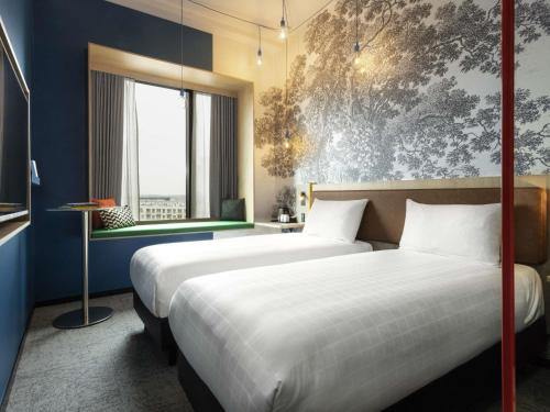 a hotel room with two beds and a window at ibis Styles Copenhagen Orestad in Copenhagen