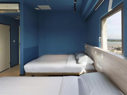 a blue room with two beds and a window at ibis budget Phnom Penh Riverside in Phnom Penh