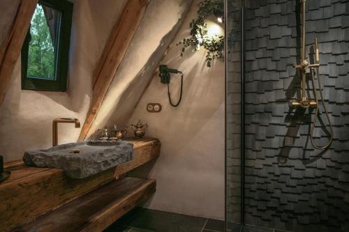 a bathroom with a stone sink and a shower at Castelul de Lut - Eco Boutique Guesthouse in Porumbacu de Sus