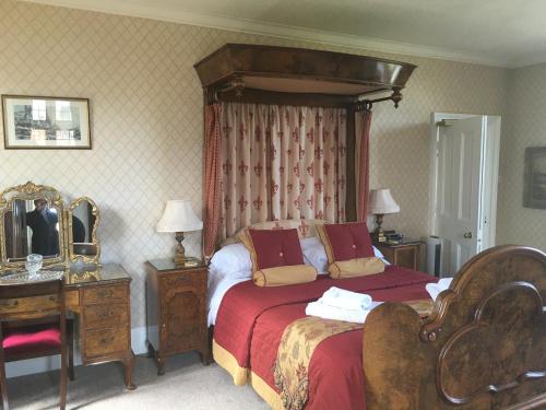 a bedroom with a bed and a dresser and a mirror at Dunsley Hall Country House Hotel in Whitby