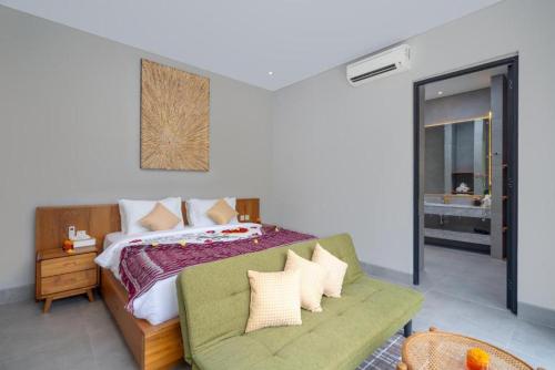 a bedroom with a bed and a green couch at The Garden Villas in Ubud
