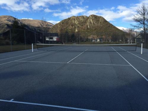 a tennis court with mountains in the background at Arrowfield Apartments in Arrowtown