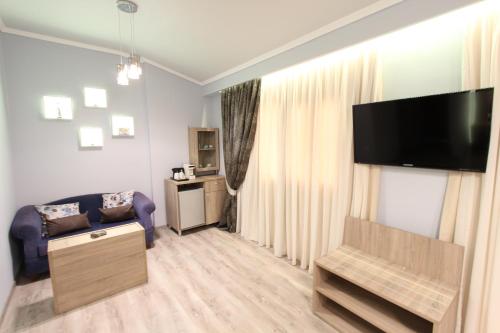 a living room with a couch and a flat screen tv at Hotel Mallas in Nea Kalikratia