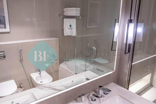 un bagno con lavandino, WC e specchio di Bloomfields Sea View 2br Apartment a Fujaira