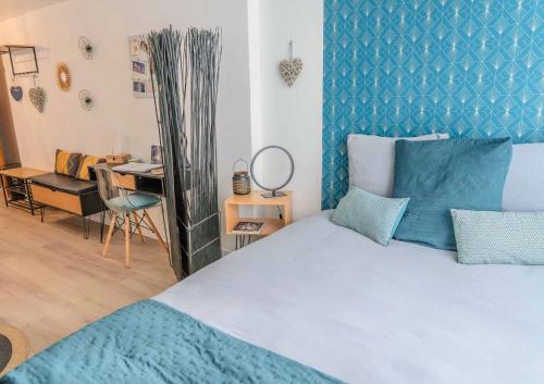 1 dormitorio con 1 cama con cabecero azul y escritorio en L'Appart'Mans -charmant-studio-centre ville-2 pers, en Le Mans